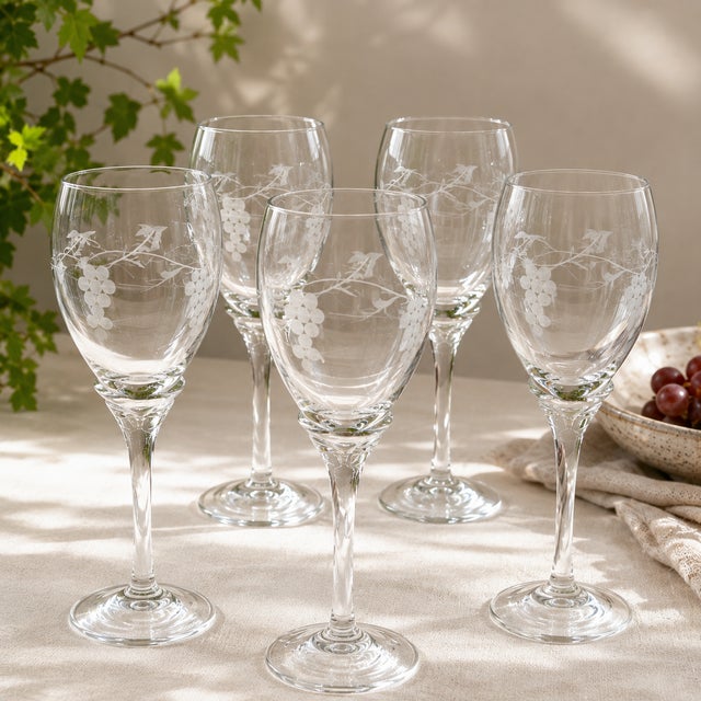 Elegant set of five vintage clear glass wine glasses featuring a delicate etched grape and vine motif. The gently rounded...