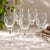 Elegant set of five vintage clear glass wine glasses featuring a delicate etched grape and vine motif. The gently rounded...