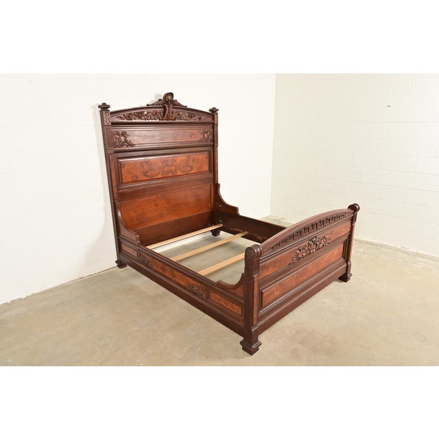 An outstanding antique Eastlake Victorian carved walnut and burl wood queen size bed frame In the manner of Herter...