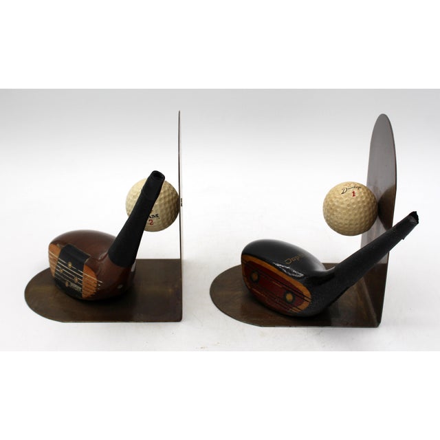 Pair of vintage golf themed bookends, American. Golf balls & driver heads (one a Top Flite by Spaulding) in brass bookend...