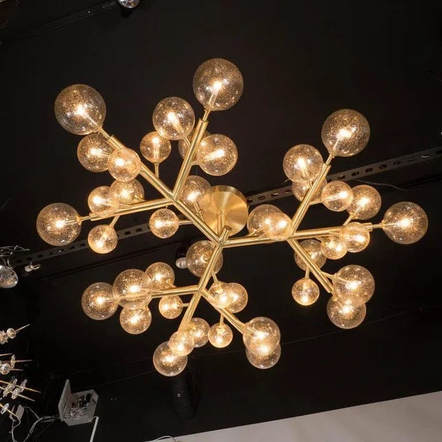 A custom and high style deco exclusive brass and Murano glass molecular "Snowflake" chandelier. A polished brass tubular...