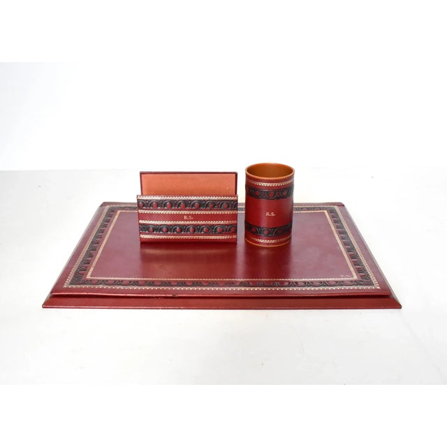 A vintage Florentine Italian red leather desk set wihth black and gold gilt embossed border designs, including a blotter,...