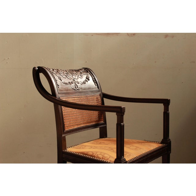 Regency style carved armchair with caned back, intricately carved crest rail and upholstered seat. Dimensions: 21.5"W x...