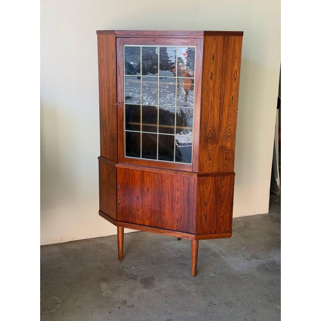 Mid Century Modern Danish corner cabinet crafted in richly grained rosewood, featuring dramatic natural figuring and warm...