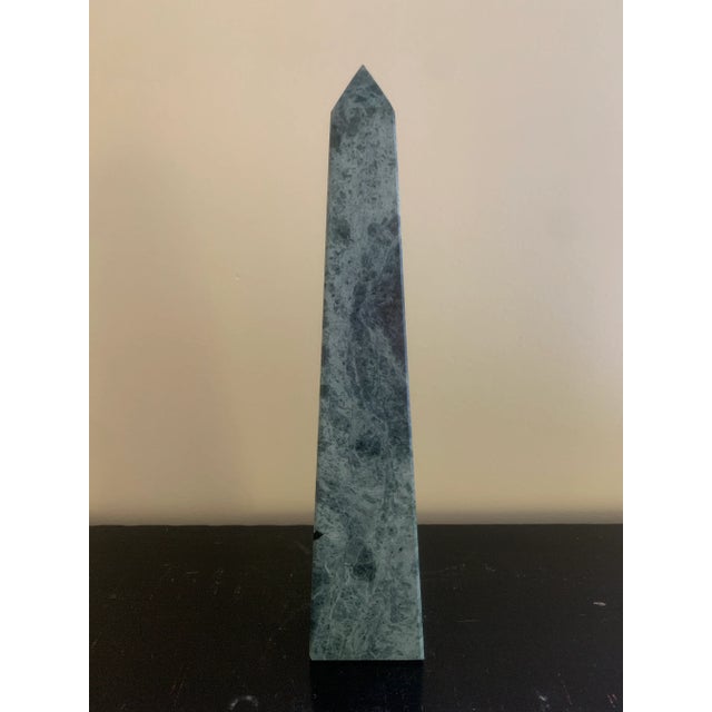 A beautifully proportioned marble obelisk in richly veined shades of green, cream, and grey. The sculptural silhouette and...