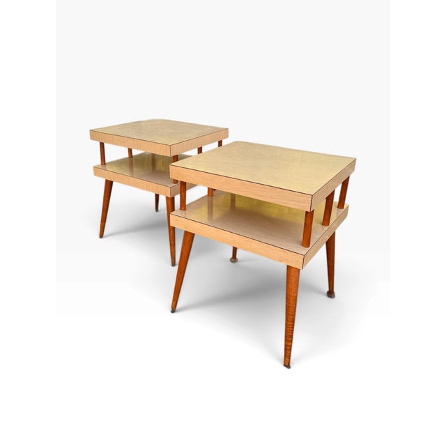 A stylish pair of vintage Mid-Century Modern two-tier end tables with a clean, architectural profile and warm natural wood...