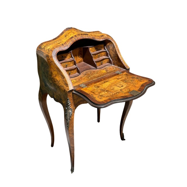 A charming Louis XV style bombe shape table crafted with figured walnut and delicate marquetry decoration with the motifs...