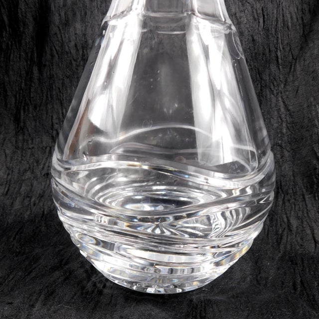 This is a large round cut crystal decanter with wavy lines cut into the bottom section of it. It has a sticker stating it...