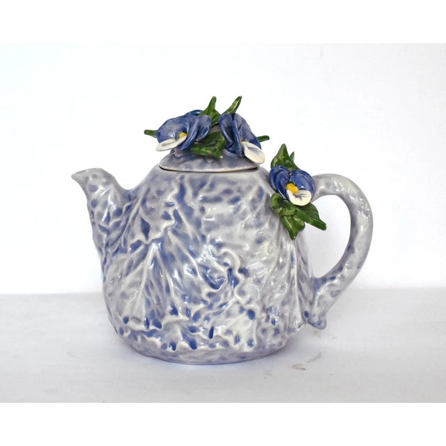A vintage ceramic pottery lavender-blue cabbageware teapot with the body of trompe l'oeil cabbage leaves, and with blue,...