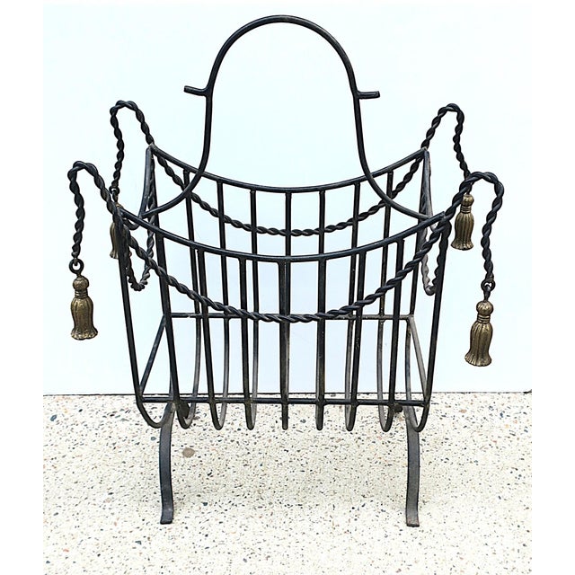 A substantial iron fireplace firewood log holder with tassel design, circa mid to late-20th century. Basket is black with...