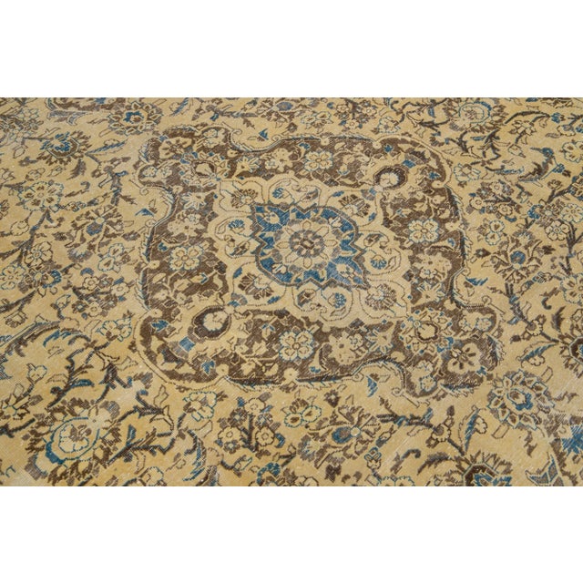 This vintage Tabriz rug boasts a beige color field and features exquisite, hand-knotted wool construction complemented by...