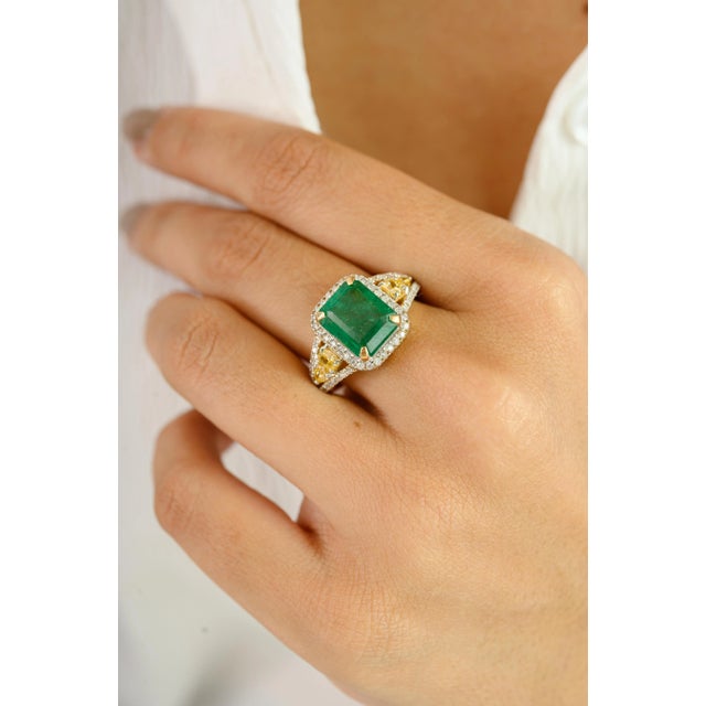 This exquisite ring is crafted in luxurious 14k yellow gold, featuring a vibrant 3.46 carat emerald-cut green gemstone as...