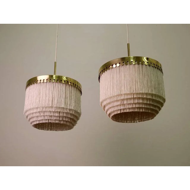 White fringes and brass. Produced by Hans-Agne Jakobsson, Markaryd, Sweden, 1960s. Height is adjustable. This piece is...