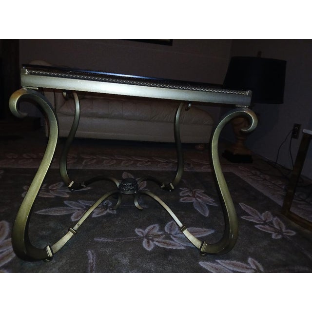 Modern Mid-1990's gracefully scrolled metal table in burnished gold finish. 24" square. Thick beveled glass top sits on...