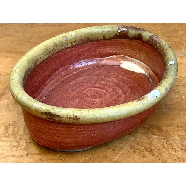 Hand-thrown with rich artisanal texture and traditional earth tones, this vintage studio pottery oval vessel features a...