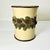 This is an attractive Rustic wastebasket. It has a ring of dark green pine tree branches with brown pinecones encircling...