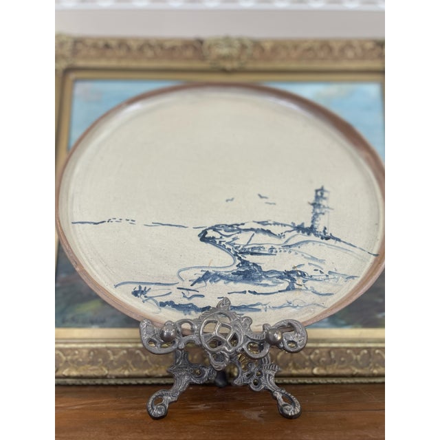 Large handcrafted studio pottery dish featuring a hand-painted coastal scene in cobalt blue, depicting a rocky shoreline...