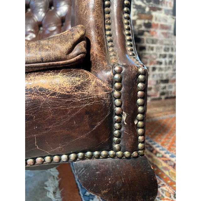 The classic sophistication of this Antique English Chesterfield Leather Wing Back Chair will elevate any space it resides...