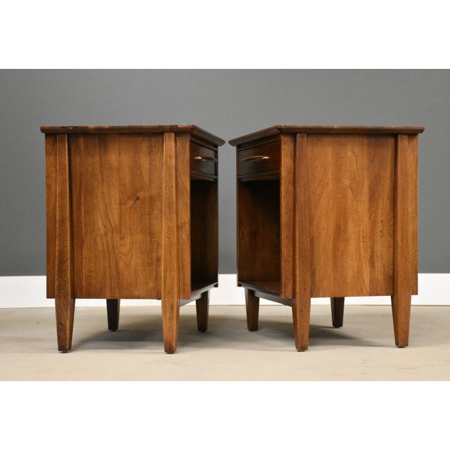 A pair of mid century modern walnut single drawer nightstands with enlongated walnut drawer pulls made by Davis Cabinet...