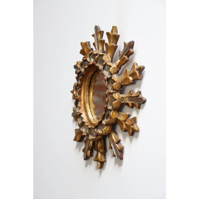 Diminutive sun/starburst wall mirror composed of giltwood, carved to resemble foliage, with inset mirror glass (ca. 1940s,...