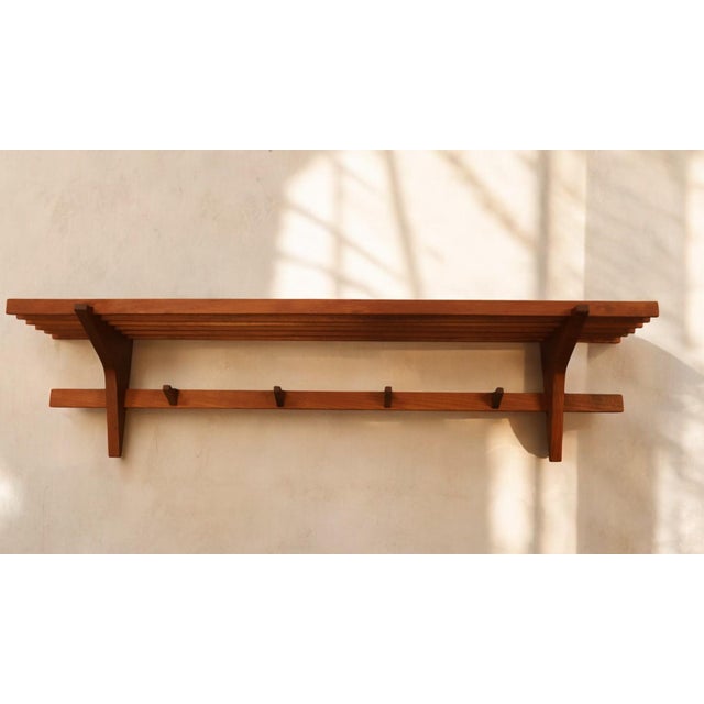 Danish hat rack in solid teak with four hooks. Ribbed shelf for hats, storage box etc. and four hooks that are also in...