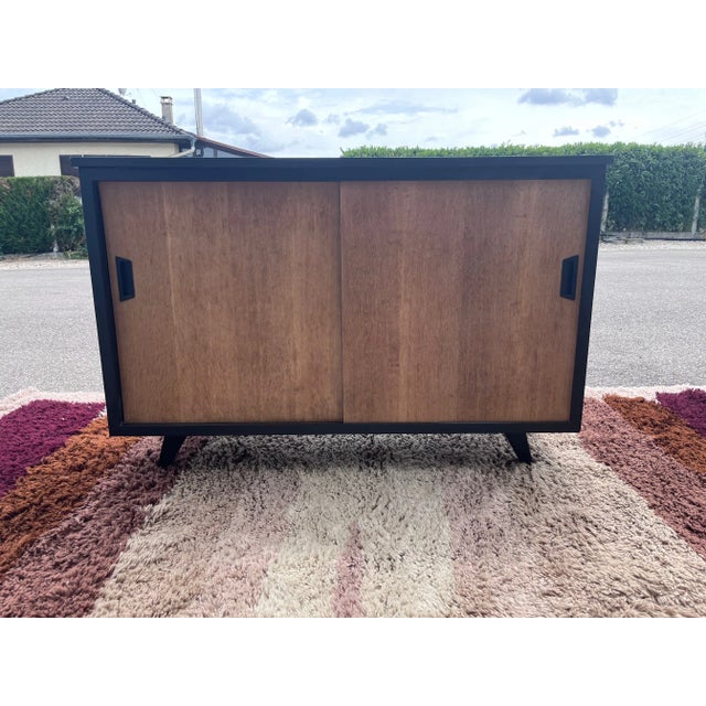 cabinet with sliding doors in raw wood opening onto 4 compartments, black lacquered structure