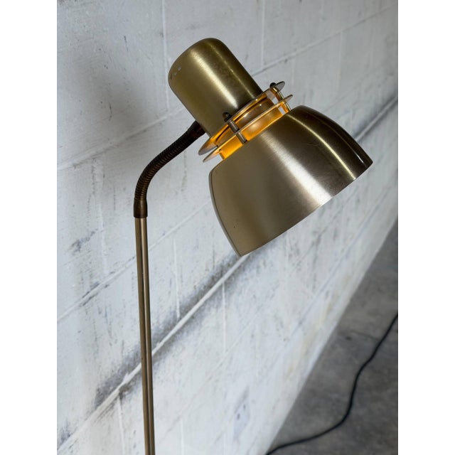 This sleek floor lamp features a minimalist profile with a single directional spotlight. The adjustable head allows for...