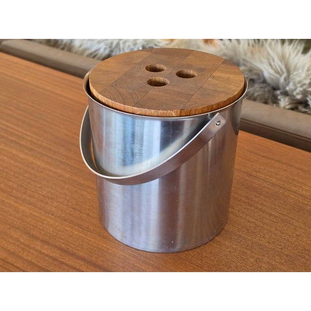 This mid-century modern ice bucket combines durable stainless steel with a warm, teak wood lid. Designed in a classic...