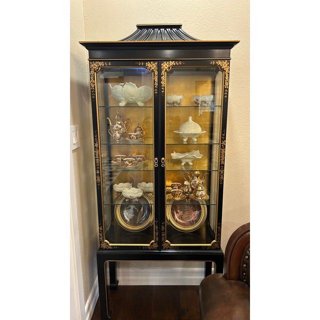 Vintage Chinoiserie China Cabinet of unknown origin, with gold decorating painted on black wood.
