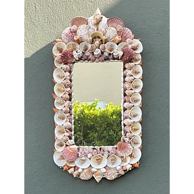 This vintage shell-encrusted mirror presents a romantic, arched silhouette, with a rectangular mirrored panel framed by a...