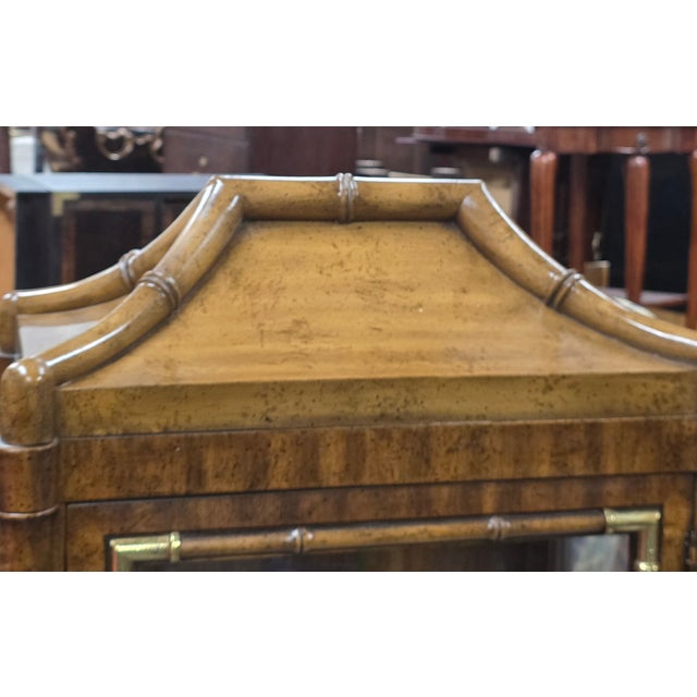 This Pair of Mid-Century Weiman Faux Bamboo Burl Pagoda Vitrines on Matching Cabinets (4 Pieces)is a commanding and...