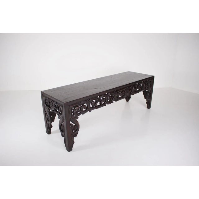 Console carved in blackened solid wood called “hongmu”, decorated with scrolls and dragons in central medallion. China,...