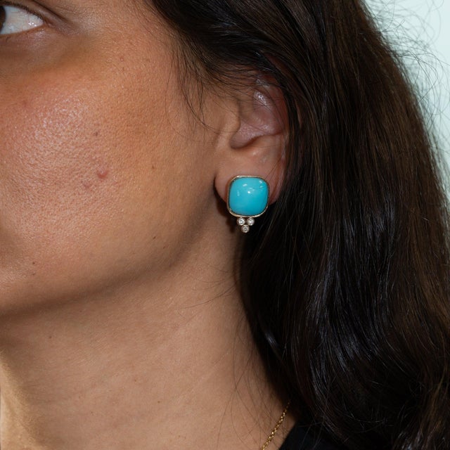 A bold pair of Sleeping Beauty turquoise cabochons in clean, robin's-egg blue anchors these solid 14K yellow gold stud...