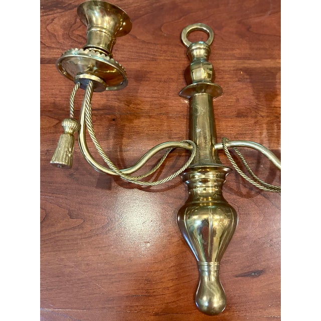 Offering a charming brass candle sconce in classic braid and tassel design.