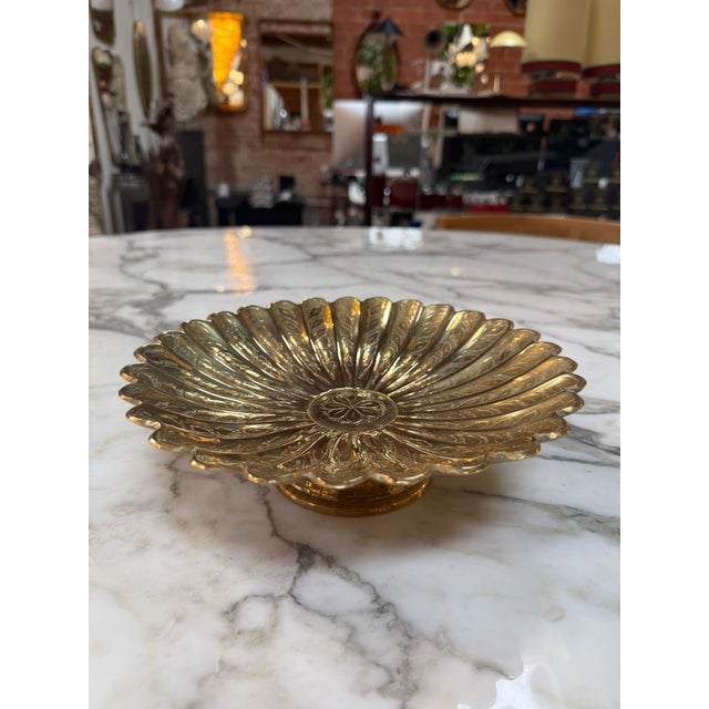 Elegant vintage solid brass pedestal bowl featuring a dramatic fluted shell-inspired design with a scalloped rim and...