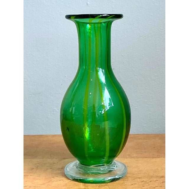 This vase presents a graceful, bulbous silhouette in richly saturated green glass, its rounded body swelling generously...
