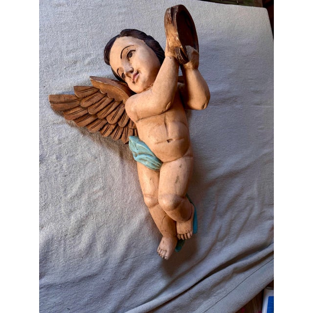 A charming and expressive hand-carved wooden putto (cherub angel) in the Italian Baroque tradition. The figure is depicted...