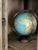 A circa 1930 8-inch Standard Globe by Replogle features seafoam green oceans and warm ochre and coral landmasses, set...