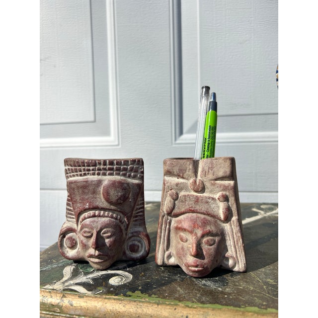 Small tribal head planters or vases for dried flowers. These are made of clay and are not glazed, so we don’t believe they...