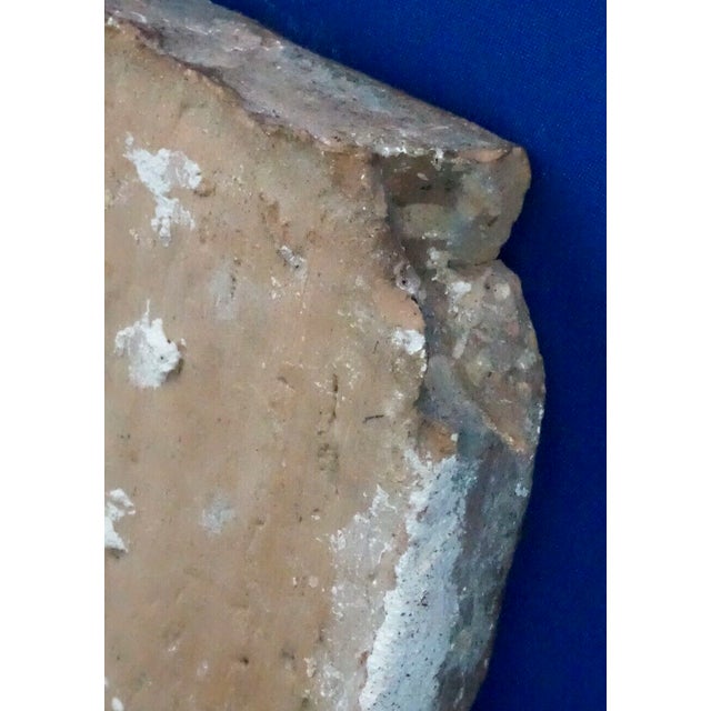 Item description: A thick, heavy, extremely hard terracotta brick dating back to the 1500s, decorated with a heraldic coat...