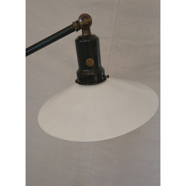 Very unique industrial floor lamp with cast iron belt wheel base. milk glass shade and braided fabric cord. 3 adjustment...