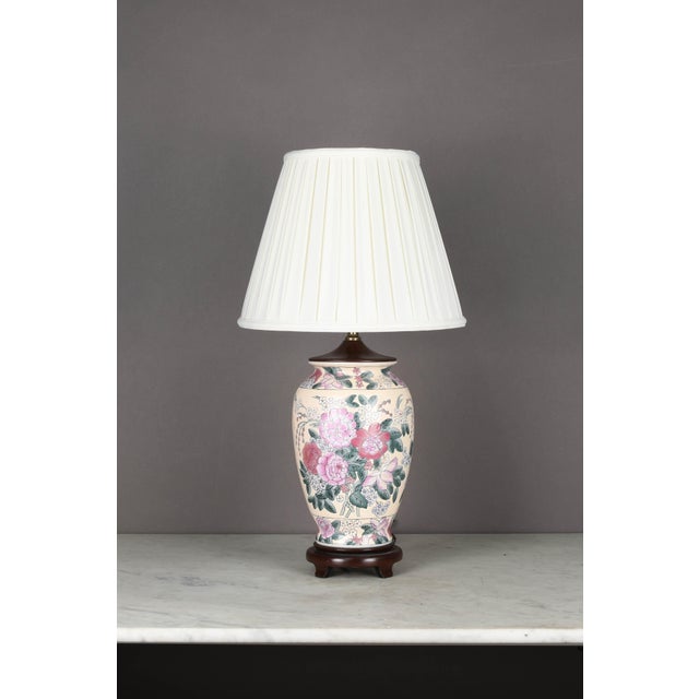 Carved & painted pink floral and leafy green pattern on a cream glazed porcelain ginger jar with dark wooden base and lid....