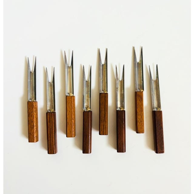 A set of 8 mid century cocktail forks. Each is made of stainless steel with wood handles. Perfect for using as appetizer...