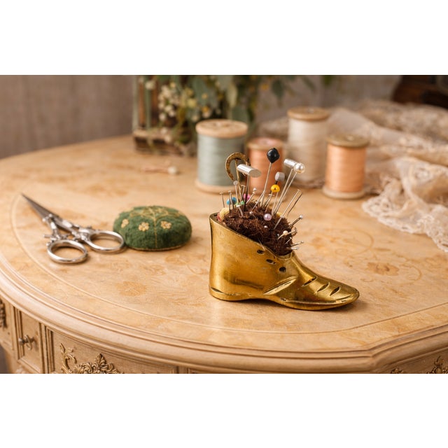 This charming antique brass boot pincushion originates from England and dates to the late Victorian to early Edwardian...