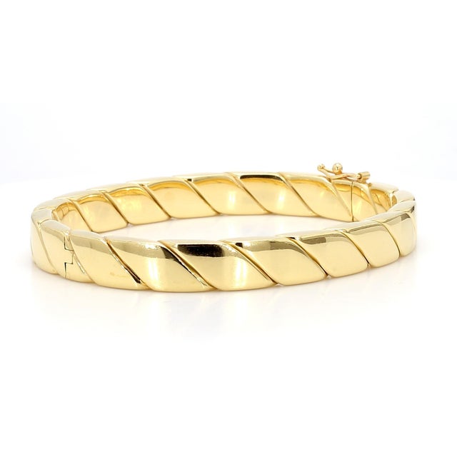 Tiffany and Co signed 18K yellow gold hinged bangle bracelet featuring a flat box-profile twisted rope design with a high-...