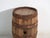 This antique wooden barrel with iron hoops features a cylindrical body of oak staves held by hand-forged iron hoops and a...