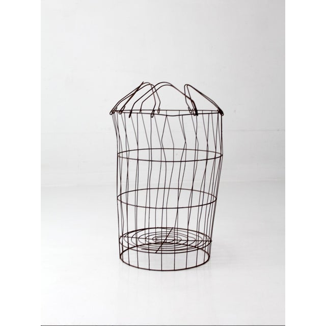 An antique wire gathering basket with a tall, airy profile and expressive hand-bent construction. Its generous scale lends...