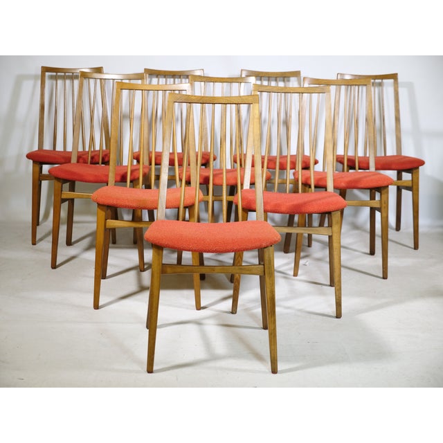 Ten mid-century dining chairs in walnut from the 1960s. Slender wooden frames with slightly splayed legs and high backs...