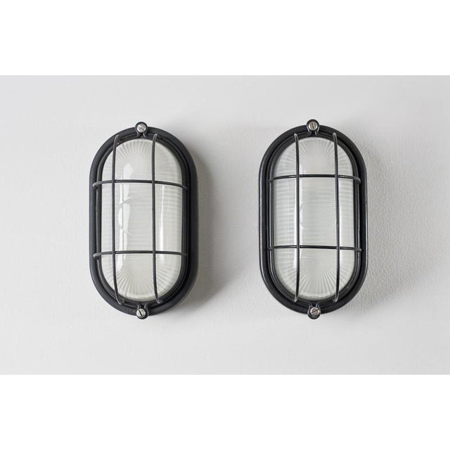 Industrial wall lamp dates from the 1970s, features the classic oval "bulkhead" or "turtle" design. The fixture is...