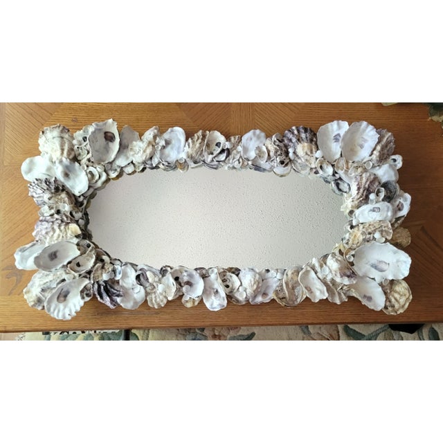 OYSTER WALL MIRROR Multiple layers of natural oyster shells with small white scallop cup shells scattered throughout. The...